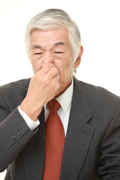 Senior Japanse zakenman zijn neus te houden vanwege een slechte geur — Stockfoto