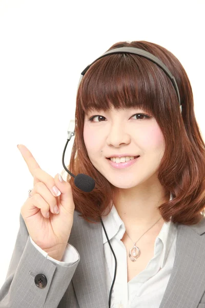 Joven japonesa empresaria de call center con cabezales presentando y mostrando algo —  Fotos de Stock