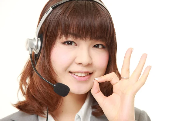 Joven mujer de negocios japonesa de call center con conjuntos de cabeza mostrando signo perfecto — Foto de Stock