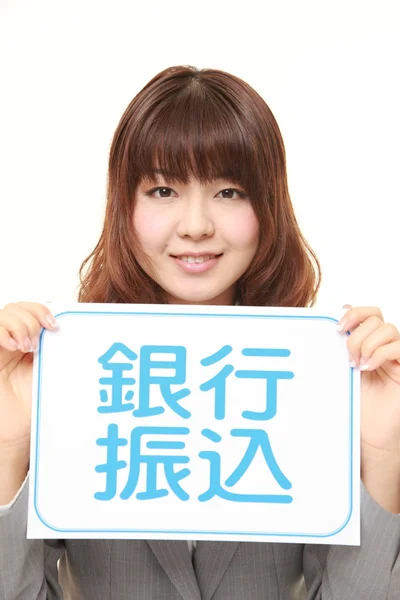 Affärskvinna innehar en anslagstavla med frasen bank överföring i Kanji — Stockfoto