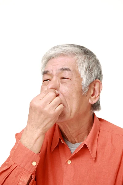 Senior japonés hombre sosteniendo su nariz a causa de un mal olor —  Fotos de Stock