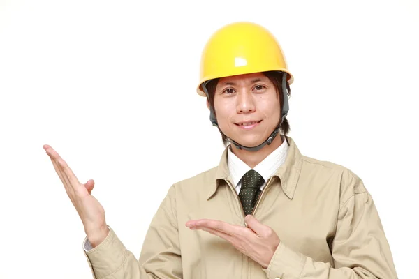 Joven trabajador de la construcción japonés presentando y mostrando algo —  Fotos de Stock