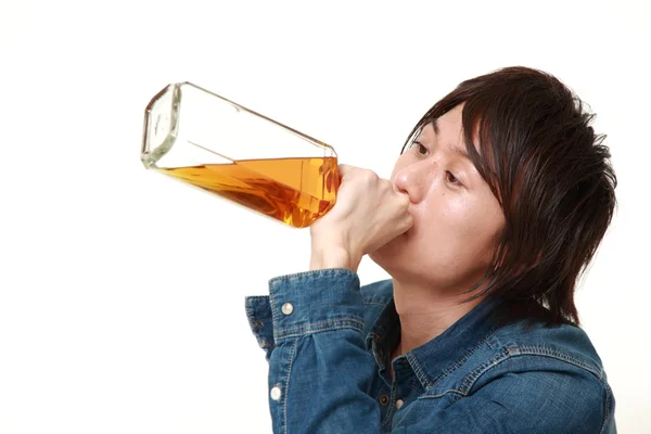 Jonge Japanse man drinken rechtstreeks uit een fles — Stockfoto