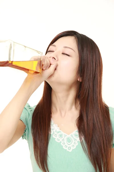 Young Japanese woman drinking straight from a bottle — Stock Photo, Image