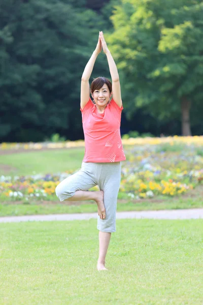 Japanese woman outside doing yoga tree pose — Stock Photo, Image