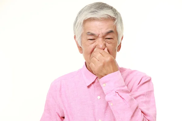 Senior japonés hombre sosteniendo su nariz a causa de un mal olor —  Fotos de Stock