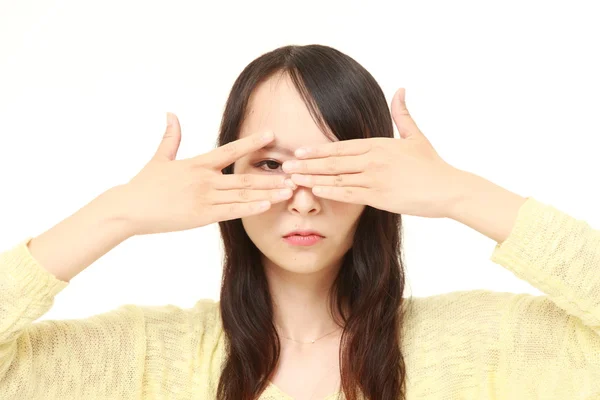 Mujer cubriéndose la cara con las manos mirando a la cámara a través de sus dedos —  Fotos de Stock