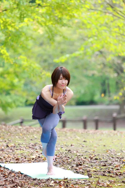 Japonesa mujer afuera haciendo yoga águila pose —  Fotos de Stock