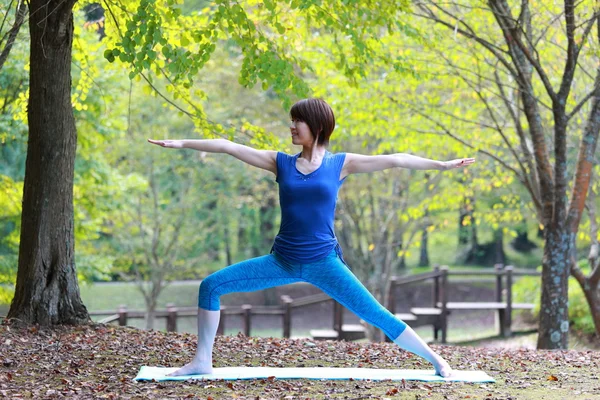 Japanese woman outside doing yoga warrior II pose — Stock Photo, Image