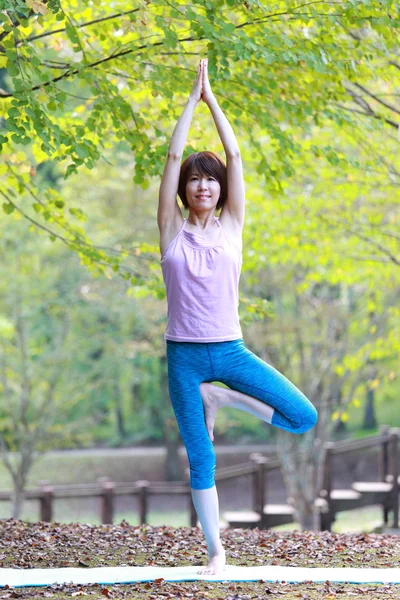 Japanese woman outside doing yoga tree pose — Stock Photo, Image