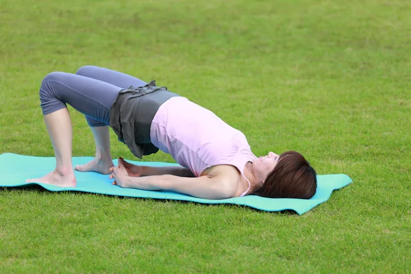 Japanese woman outside doing yoga Bridge Pose — Stock Photo, Image