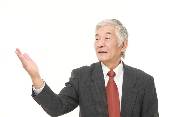Empresário japonês sênior apresentando e mostrando algo — Fotografia de Stock