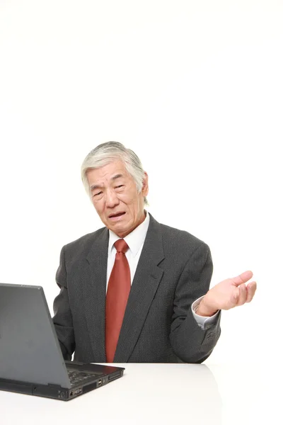 Senior Japanse zakenman met behulp van de computer op zoek verward — Stockfoto