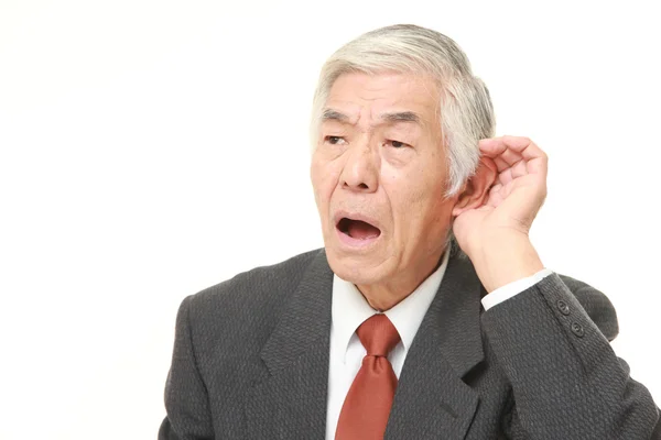 Yakından dinlerken kulak arkasında el ile üst düzey Japon işadamı — Stok fotoğraf