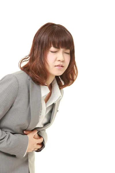Young Japanese businesswoman suffers from stomachache — Stock Photo, Image