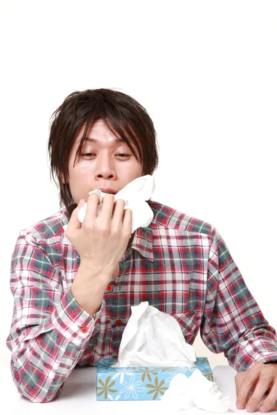 Молодой человек с аллергией чихает в ткань — стоковое фото