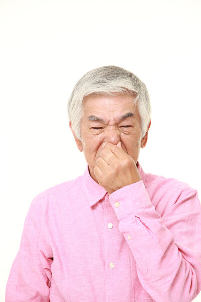 senior Japanese man holding his nose because of a bad smell