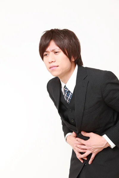 Young Japanese businessman suffers from stomachache — Stock Photo, Image