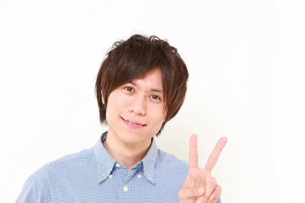 Young Japanese man showing a victory sign — Stock Photo, Image
