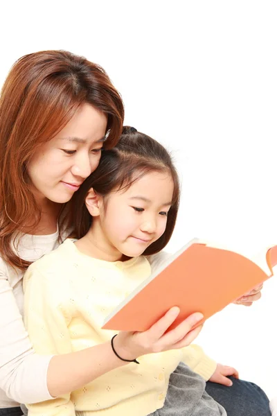 Mãe japonesa lendo um livro para sua filha — Fotografia de Stock