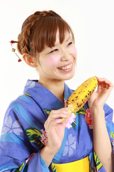 Young woman wearing Japanese kimono with grilled corn — Stock Photo, Image