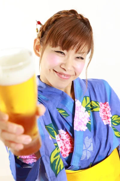 Νεαρή γυναίκα φοράει Ιαπωνικά κιμονό με ένα ποτήρι μπίρα — Φωτογραφία Αρχείου