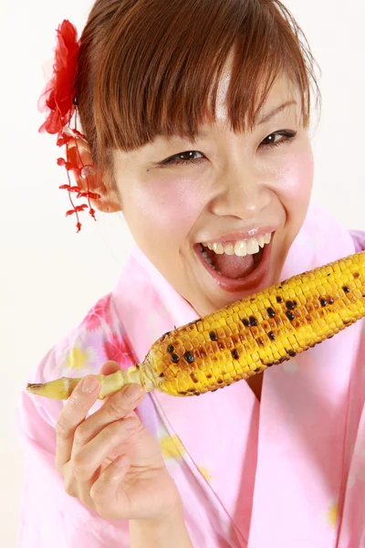 Young woman wearing Japanese kimono with grilled corn — Stock Photo, Image