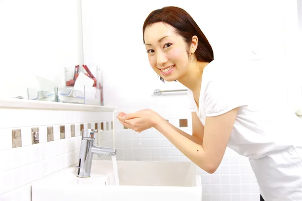 Jeune femme japonaise se lave le visage dans les toilettes — Photo