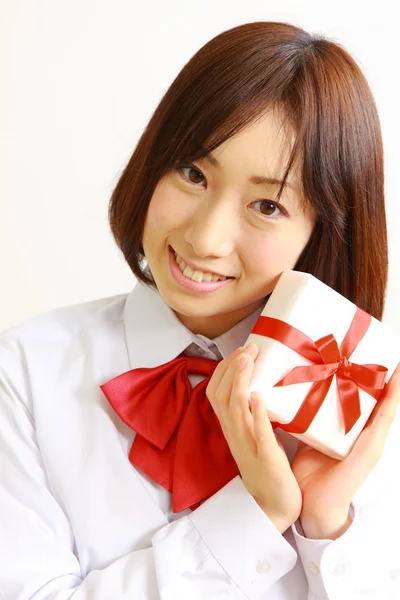 Female high school student offering a gift — Stock Photo, Image