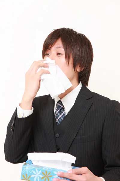 Businessman with a allergy sneezing into tissue — Stock Photo, Image