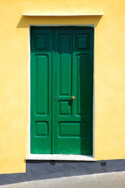 Green door on yellow wall — Stock Photo, Image