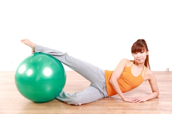 Jovem mulher japonesa fazendo exercício com bola de fitness — Fotografia de Stock