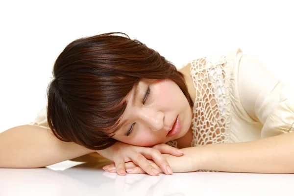 Jovem mulher japonesa dormindo na mesa — Fotografia de Stock