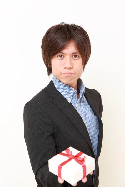 Молодой японский мужчина предлагает подарок — стоковое фото