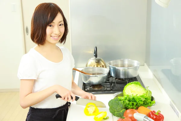 Unga japanska kvinnan kockar i köket — Stockfoto