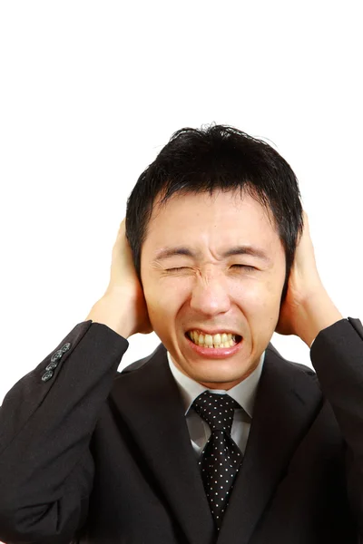 Empresário japonês de mãos dadas nos ouvidos, protegendo-se do barulho — Fotografia de Stock