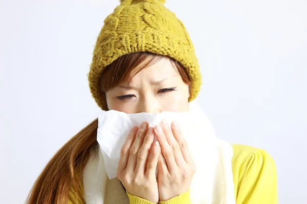 Young Japanese woman sneezing into tissue — Stock Photo, Image