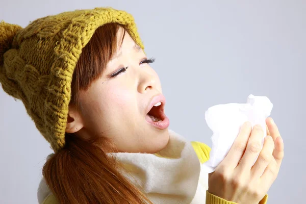 Young Japanese woman sneezing into tissue — Stock Photo, Image