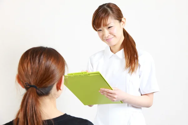 Young Japanese nurse talks with a patient — Stock Photo, Image