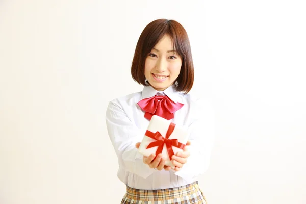 Female high school student offering a gift — Stock Photo, Image