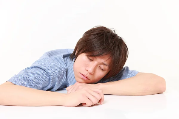 Молодой человек спит на столе — стоковое фото