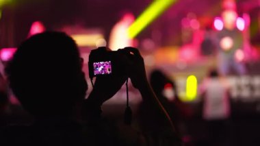 Müzik fanı kapalı alanda fotoğraf makinesiyle canlı performans konseri kaydediyor..