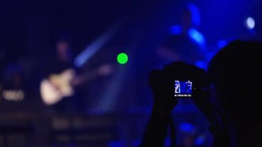Müzik fanı kapalı alanda fotoğraf makinesiyle canlı performans konseri kaydediyor..