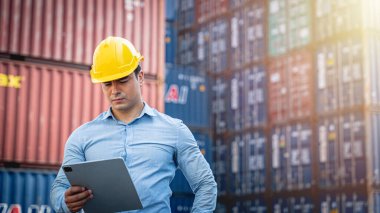 Hispanik yönetici nakliye konteynerine ithalat ve ihracat için bir tablet üzerinde envanter kontrolü yapıyor..