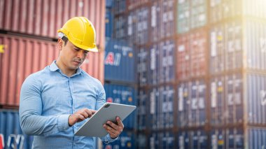 Hispanik yönetici nakliye konteynerine ithalat ve ihracat için bir tablet üzerinde envanter kontrolü yapıyor..
