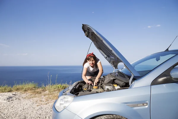 A woman repair the car, her car broke down on the road side.