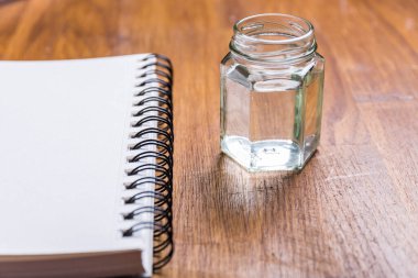 Su dolu cam bir konteynır ve ahşap bir yüzey üzerinde halka şeklinde bir boya tabakası.