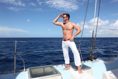 Yelkenli teknede tatilin tadını çıkaran bir adam..