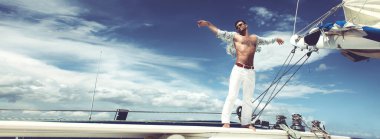 Yelkenli teknede tatilin tadını çıkaran bir adam..