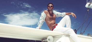 Yelkenli teknede tatilin tadını çıkaran bir adam..